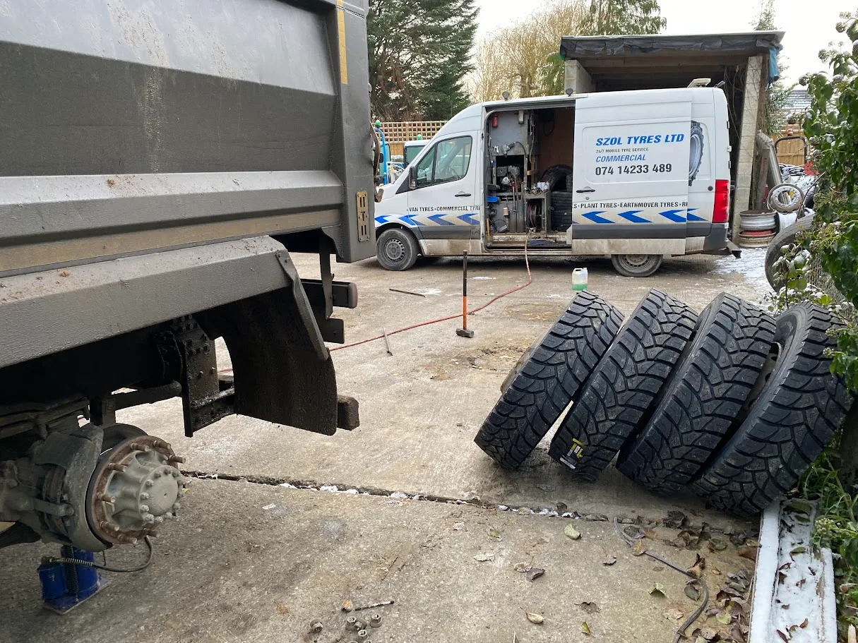 A white van is parked next to a pile of tires.
