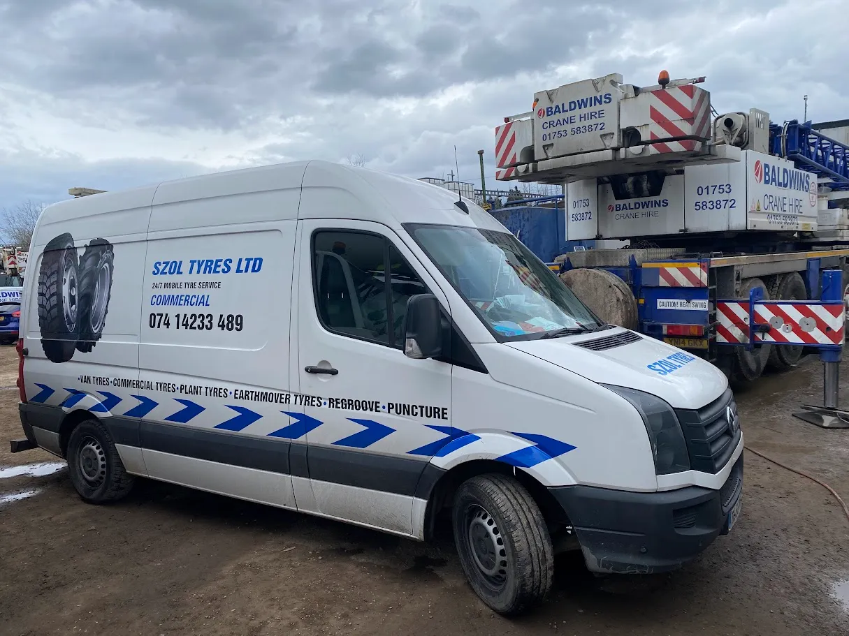 A white van parked in front of a construction site.