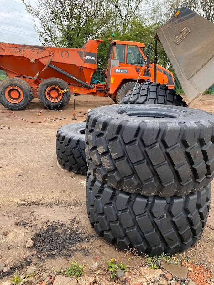 A pile of tires sitting on top of a dirt field.